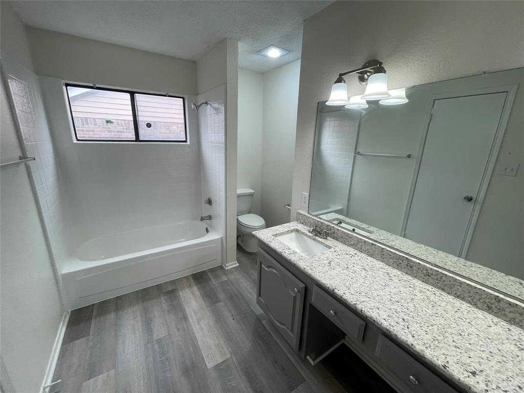 9415 Rutherglen Drive Dallas, TX 75227 - Photo 14 of 18 a bathroom with a granite countertop bathtub a sink and a mirror