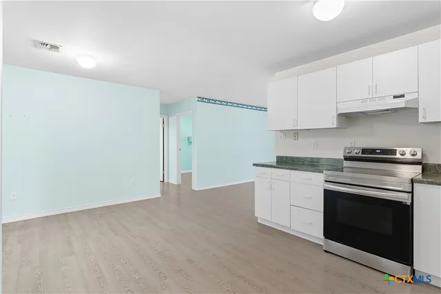 a kitchen with granite countertop white cabinets and stainless steel appliances
