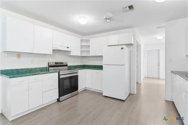 a kitchen with granite countertop white cabinets and white appliances