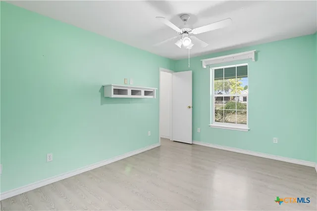 an empty room with windows and fan