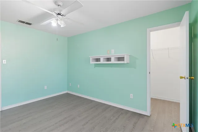 an empty room with wooden floor and ceiling fan