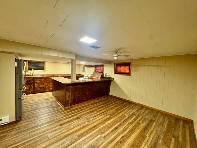 a living room with stainless steel appliances kitchen island granite countertop a sink cabinets and wooden floor