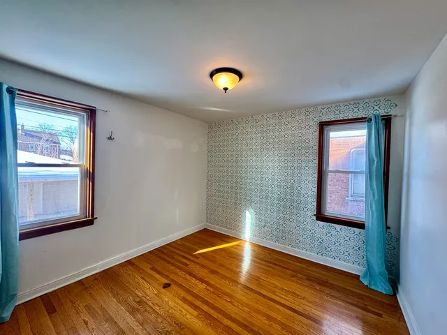 a view of empty room with window and wooden floor