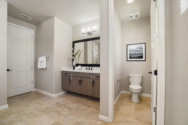 a spacious bathroom with a granite countertop toilet sink and mirror