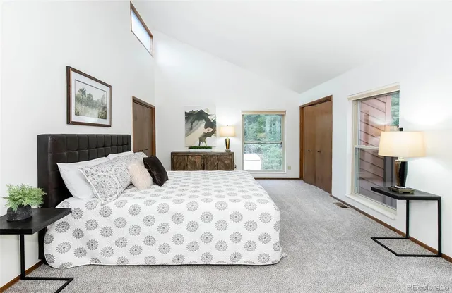 a bedroom with a large bed and a lamp on dresser