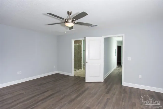 an empty room with wooden floor a ceiling fan and windows