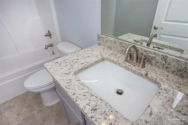 a bathroom with a granite countertop sink a toilet and bathtub
