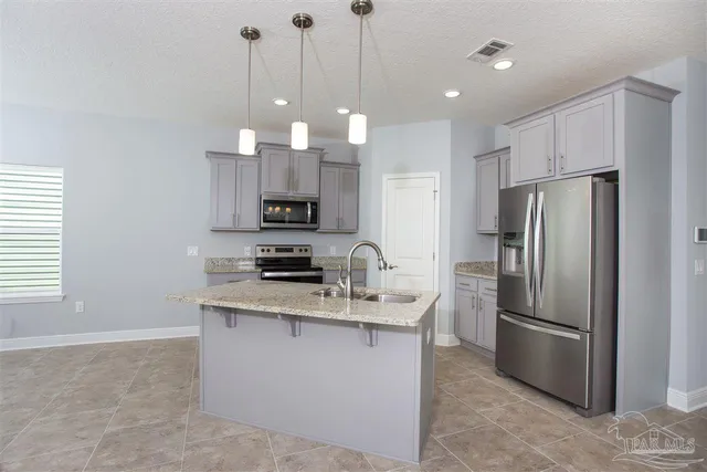 a kitchen with stainless steel appliances granite countertop a refrigerator a sink a stove a microwave and island