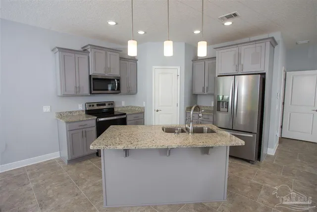 a kitchen with kitchen island granite countertop stainless steel appliances a refrigerator microwave and stove