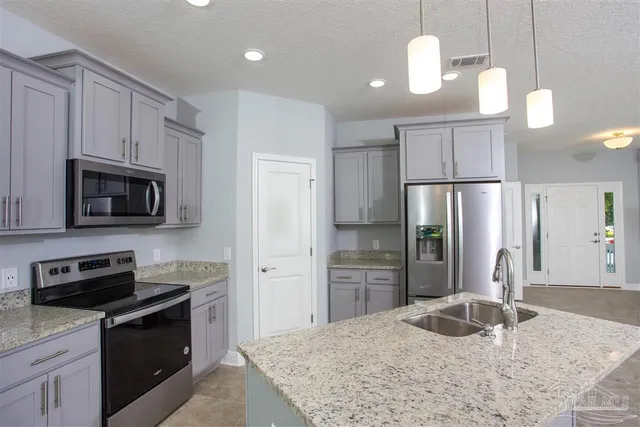a kitchen with granite countertop a refrigerator oven a sink and dishwasher