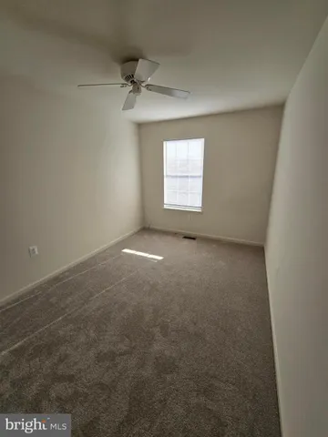 an empty room with a ceiling fan and carpet