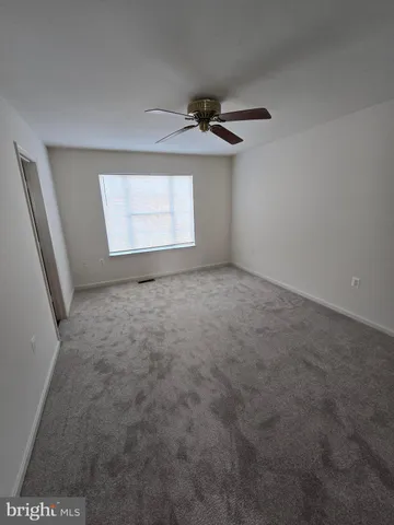 an empty room with windows and a ceiling fan