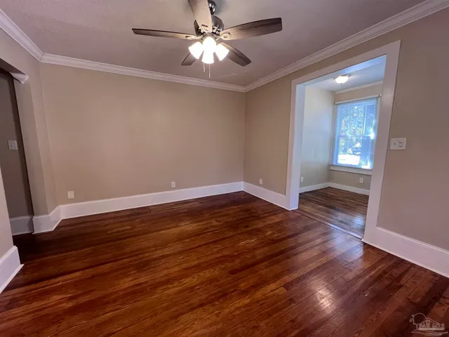 a view of empty room with wooden floor and fan