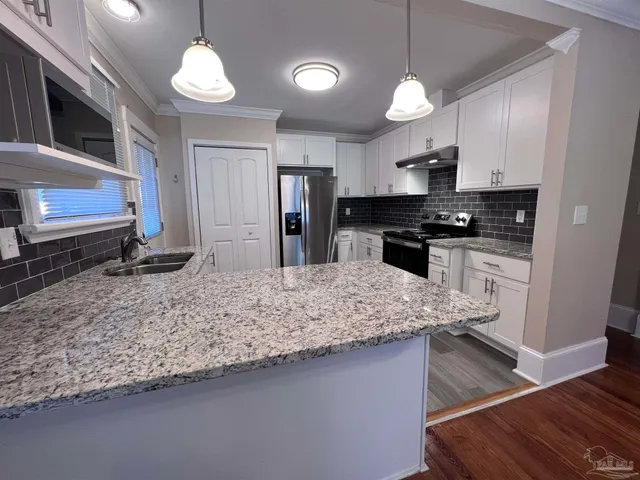 a kitchen with stainless steel appliances granite countertop a sink a stove and a microwave