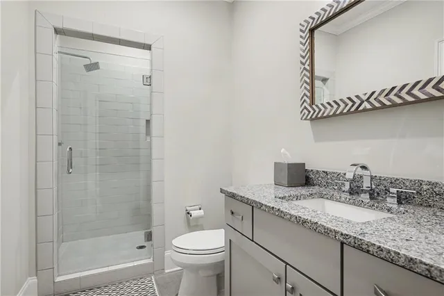 a bathroom with a granite countertop sink a toilet and shower