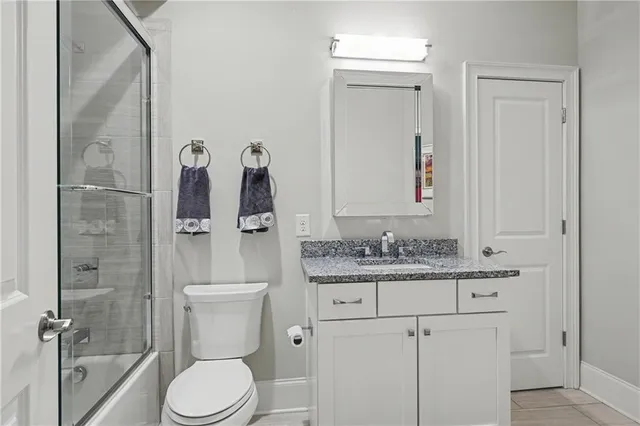a bathroom with a granite countertop toilet sink and mirror