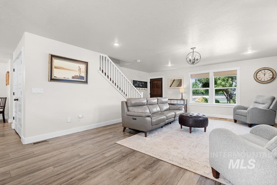 23800 Breyer Road Caldwell, ID 83607 - Photo 8 of 50 Bright living space featuring wood-finish flooring, white trim, and a white staircase with wood handrails