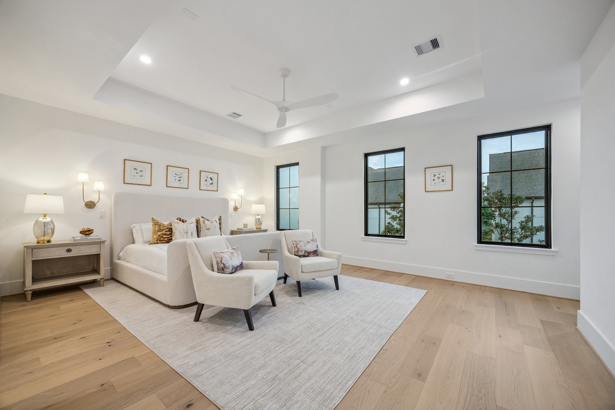 4034 Lanark Lane Houston, TX 77025 - Photo 16 of 32 The serene bedroom is designed as a calm, light-filled retreat that blends modern simplicity with soft, inviting warmth. Architectural details such as the coffered ceiling and modern ceiling fan add dimension and functionality without overwhelming the space. Clean lines, reading lights, and warm woods, complete this beautiful room. There is also a coffee bar, not shown in the photo.
