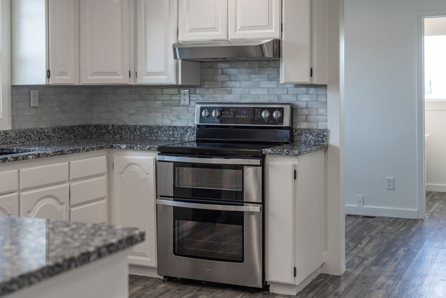 4155 Johnson Road Nibley, UT 84321 - Photo 12 of 71 Kitchen featuring dark stone counters, double oven range, white cabinetry, and dark wood-style flooring