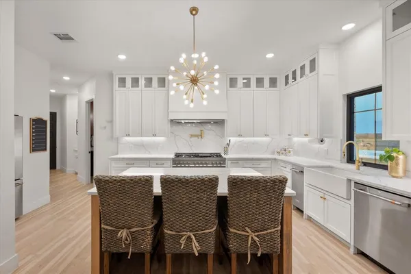 a kitchen with kitchen island granite countertop a dining table chairs sink and white cabinets