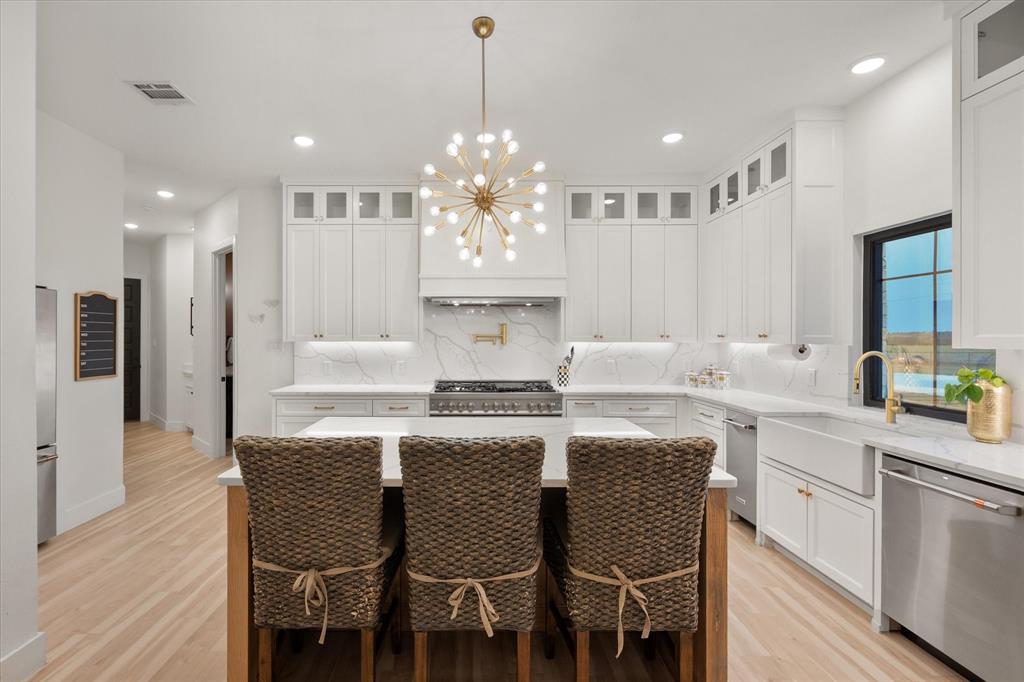 1911 Ozro Road Venus, TX 76084 - Photo 16 of 40 a kitchen with kitchen island granite countertop a dining table chairs sink and white cabinets