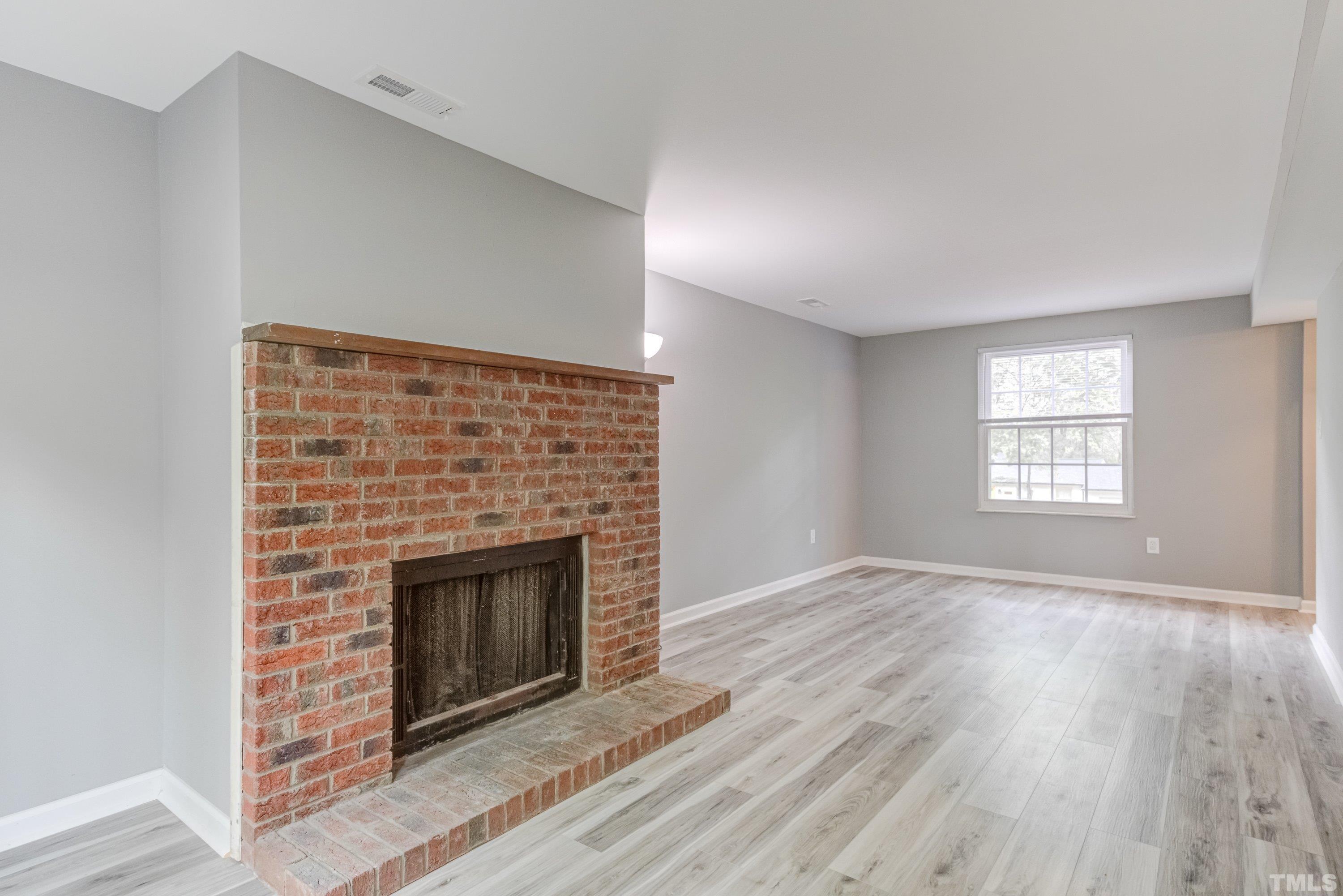 7921 Mourning Dove Road Raleigh, NC 27615 - Photo 16 of 52 an empty room with wooden floor fireplace and windows