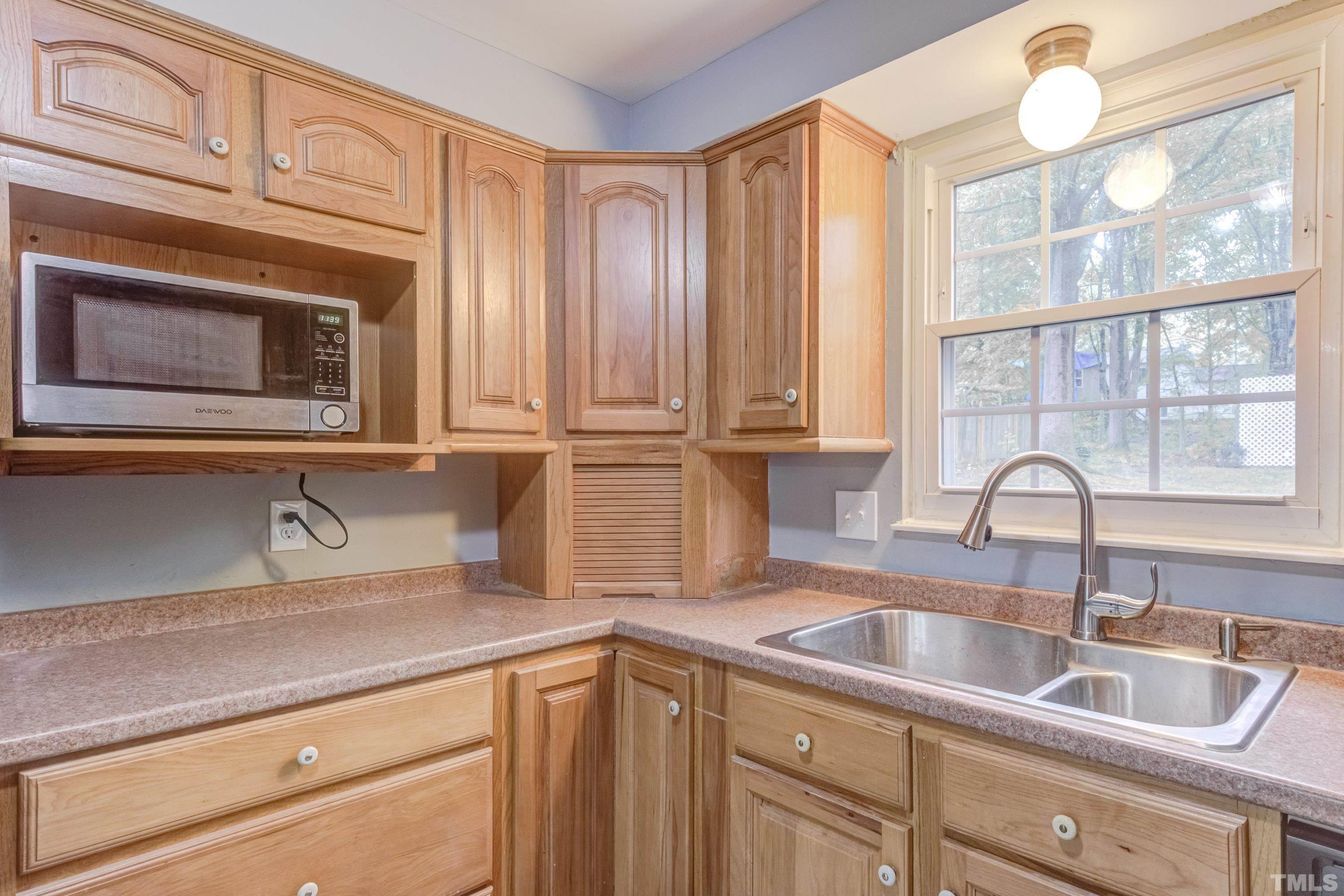 7921 Mourning Dove Road Raleigh, NC 27615 - Photo 10 of 52 a kitchen with granite countertop a sink stainless steel appliances white cabinets and a window