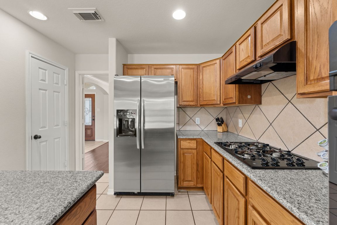 2201 Improver Road Spicewood, TX 78669 - Photo 14 of 26 a kitchen with stainless steel appliances granite countertop a sink stove and refrigerator