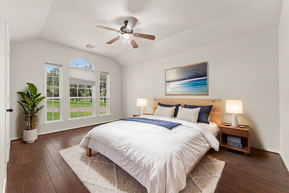 2201 Improver Road Spicewood, TX 78669 - Photo 16 of 26 a spacious bedroom with a large bed and a chandelier