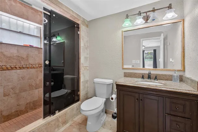 a bathroom with a granite countertop sink toilet and shower