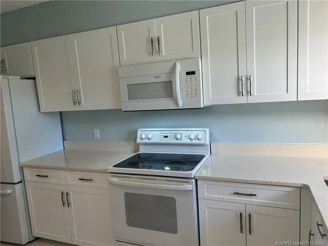 a kitchen with white cabinets and white appliances