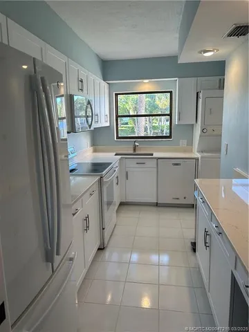 a kitchen with granite countertop a sink window and refrigerator