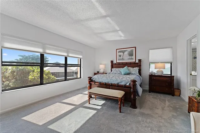 a bedroom with a bed and large windows