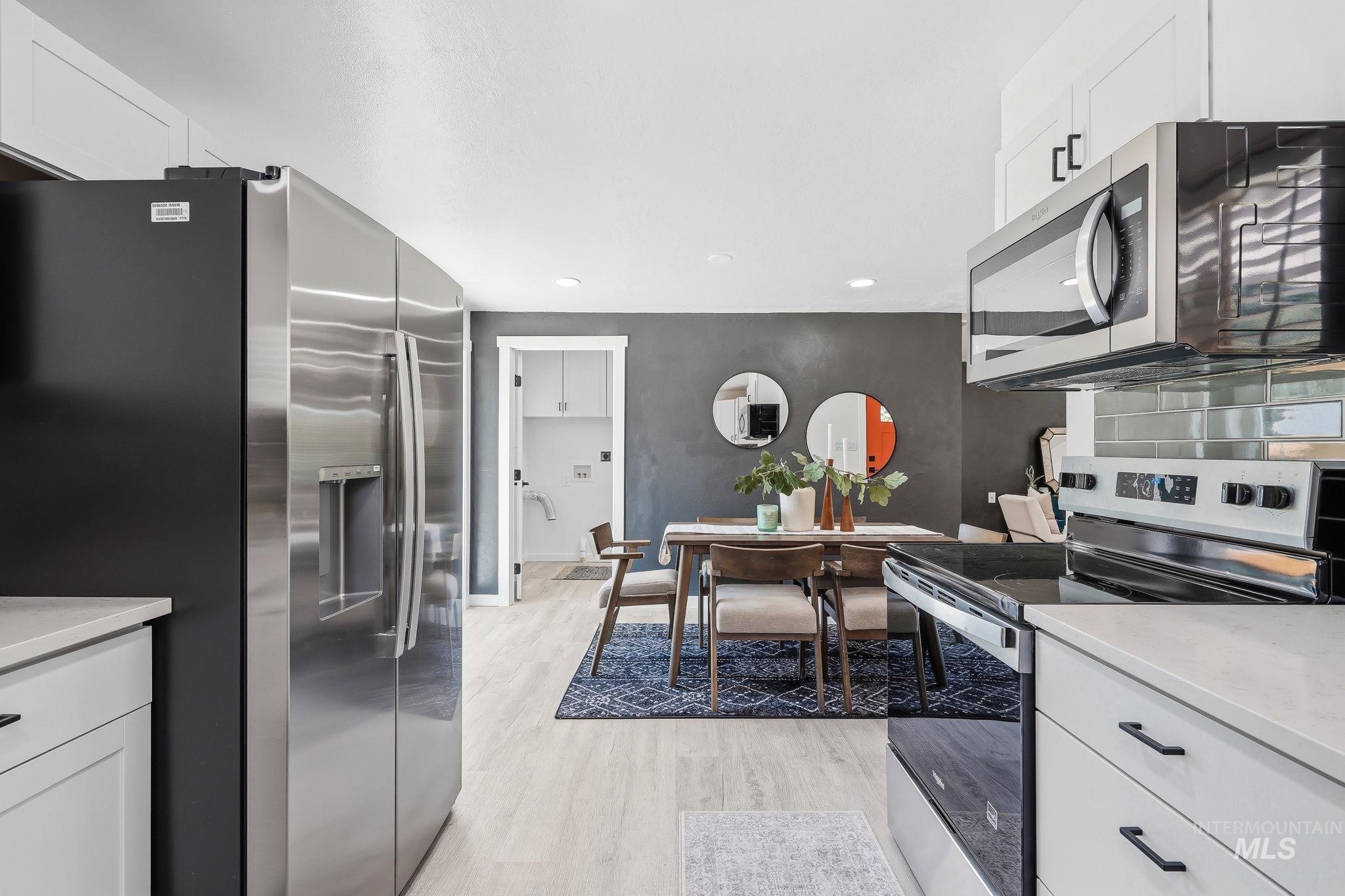 2152 Artesian Road Eagle, ID 83616 - Photo 19 of 50 Modern kitchen featuring light wood-finish flooring, white cabinetry with matte black hardware, stainless steel appliances, and light countertops
