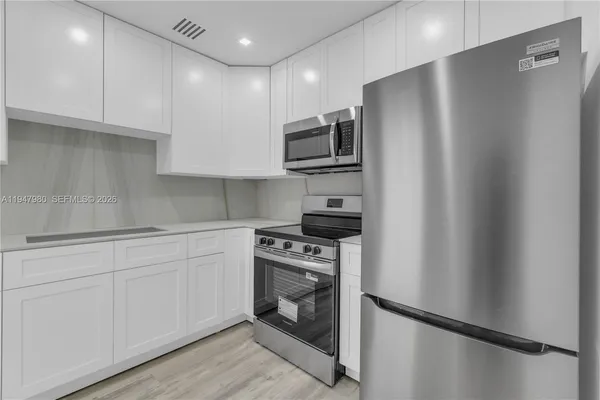 a kitchen with stainless steel appliances white cabinets and a refrigerator