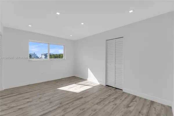 a view of empty room with wooden floor and window