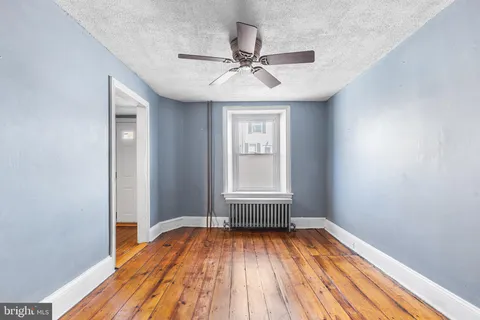 a view of empty room with wooden floor and fan