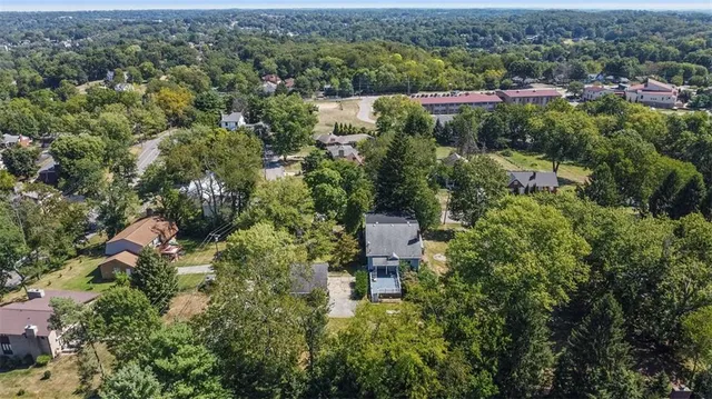 an aerial view of residential house with outdoor space and trees all around