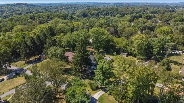 an aerial view of residential house with outdoor space and trees all around