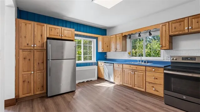 a kitchen with granite countertop stainless steel appliances a refrigerator cabinets and a wooden floor
