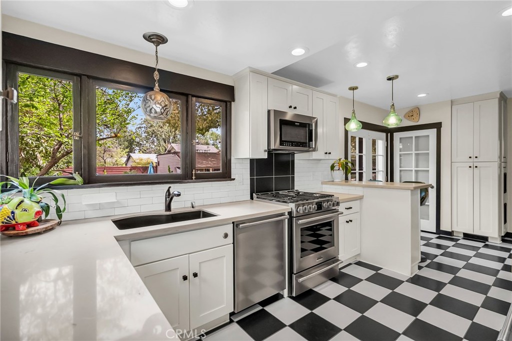4465 5th Street Riverside, CA 92501 - Photo 18 of 56 a kitchen with a sink a stove a refrigerator and black cabinets next to a window