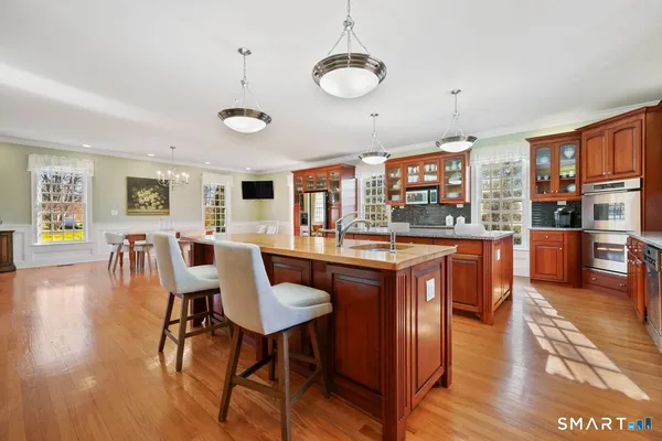 a open kitchen with stainless steel appliances granite countertop a stove top oven a dining table and chairs with wooden floor