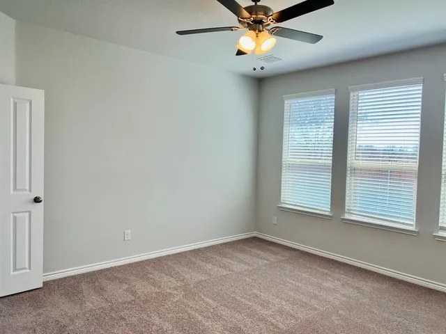 an empty room with a window and a fan