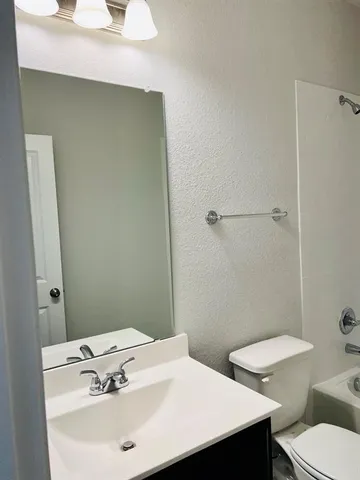 a bathroom with a sink a toilet a mirror and shower