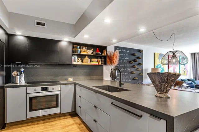 a living room with stainless steel appliances kitchen island granite countertop a stove a sink a dining table and chairs with wooden floor