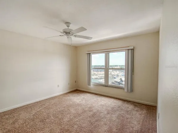 an empty room with windows and fan