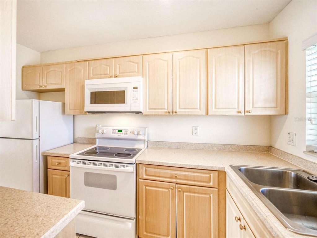 4939 Floramar Terrace, Unit 904 New Port Richey, FL 34652 - Photo 6 of 53 a kitchen with white cabinets sink and white appliances