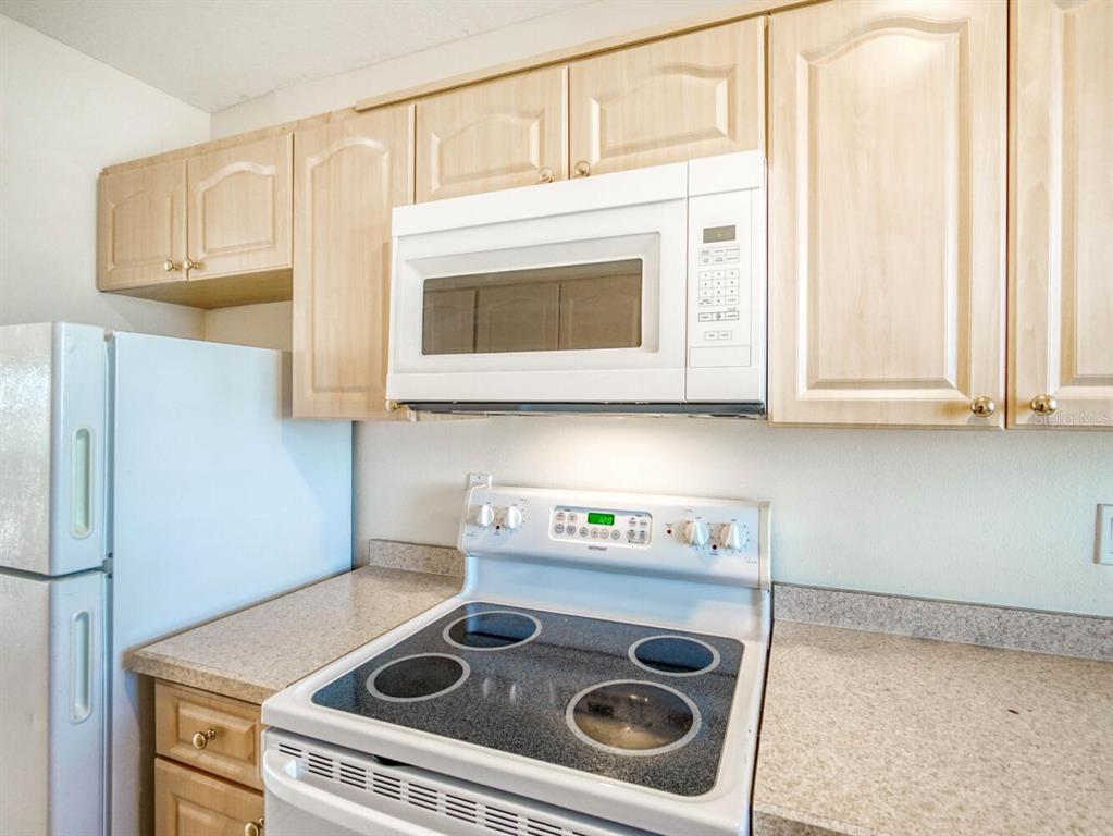 4939 Floramar Terrace, Unit 904 New Port Richey, FL 34652 - Photo 9 of 53 a kitchen with stainless steel appliances granite countertop a stove a microwave and cabinets