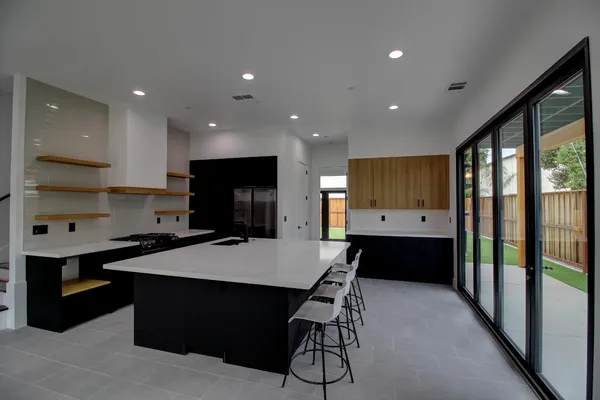 a kitchen with stainless steel appliances kitchen island granite countertop a stove a refrigerator a sink a dining table and chairs with wooden floor