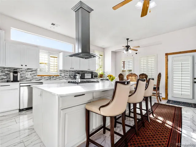 a kitchen with stainless steel appliances kitchen island granite countertop a stove a sink a dining table and chairs